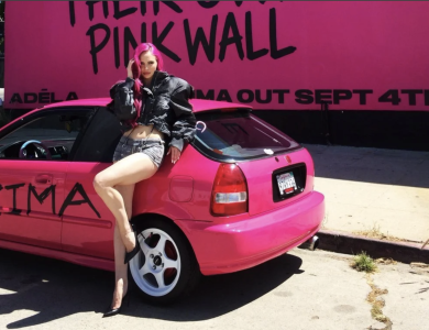 ADELA posing with a pink car in front of a pink wall